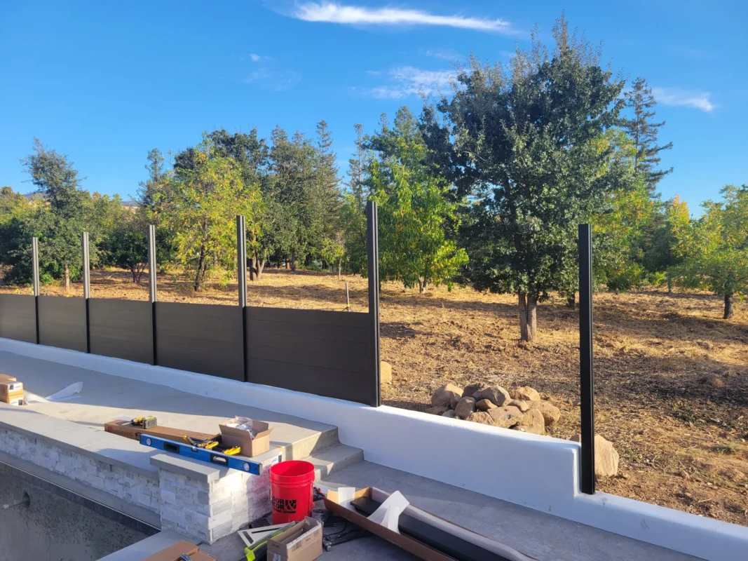 Aluminum fence installation in progress, with black posts and partially completed horizontal slats.