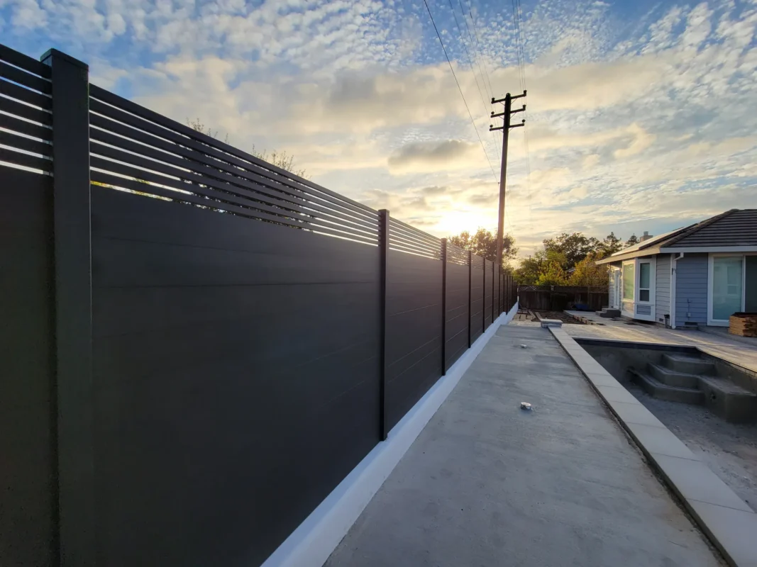 Close view along black horizontal fence slats with a spaced upper section.