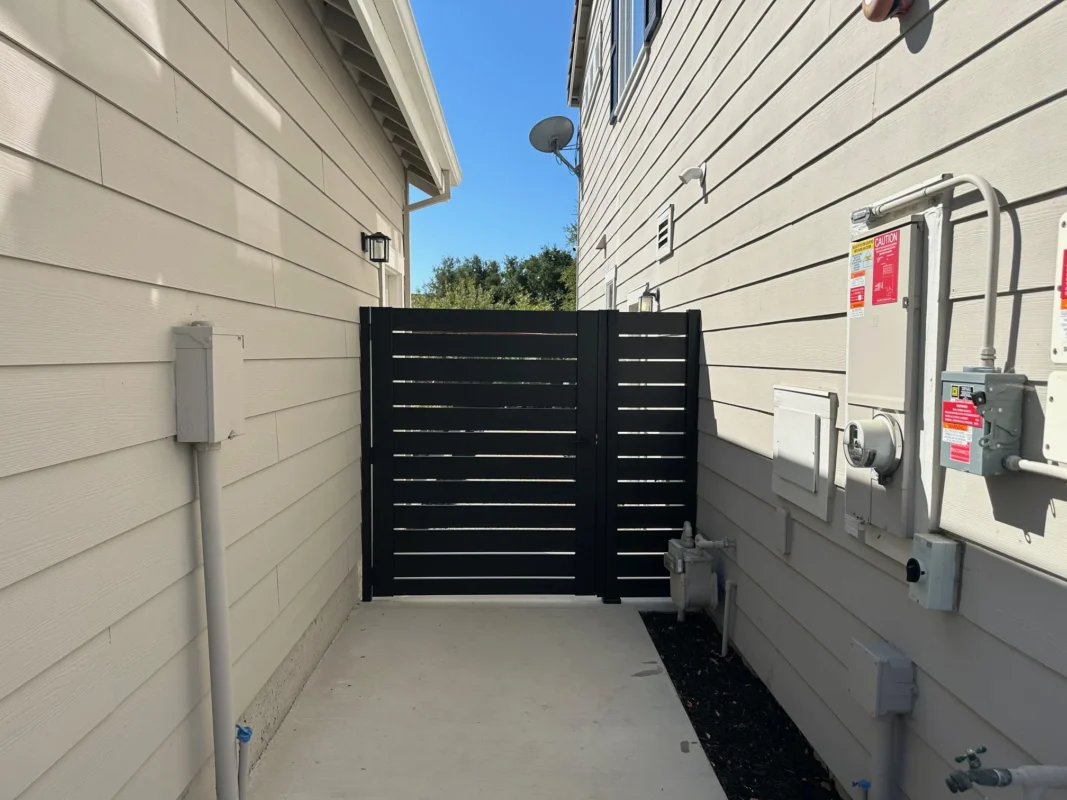 Side perspective of the black Los Angeles style gate with panel slats used as a pedestrian access gate.