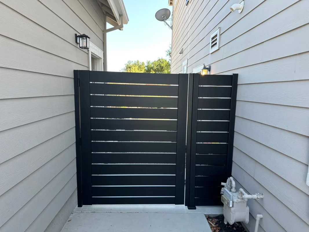Another angle showing the black horizontal slat side gate between adjacent buildings with clean modern siding.